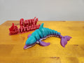 3D printed dolphin figurine in blue and purple colors on wood table with Perry's Printing sign