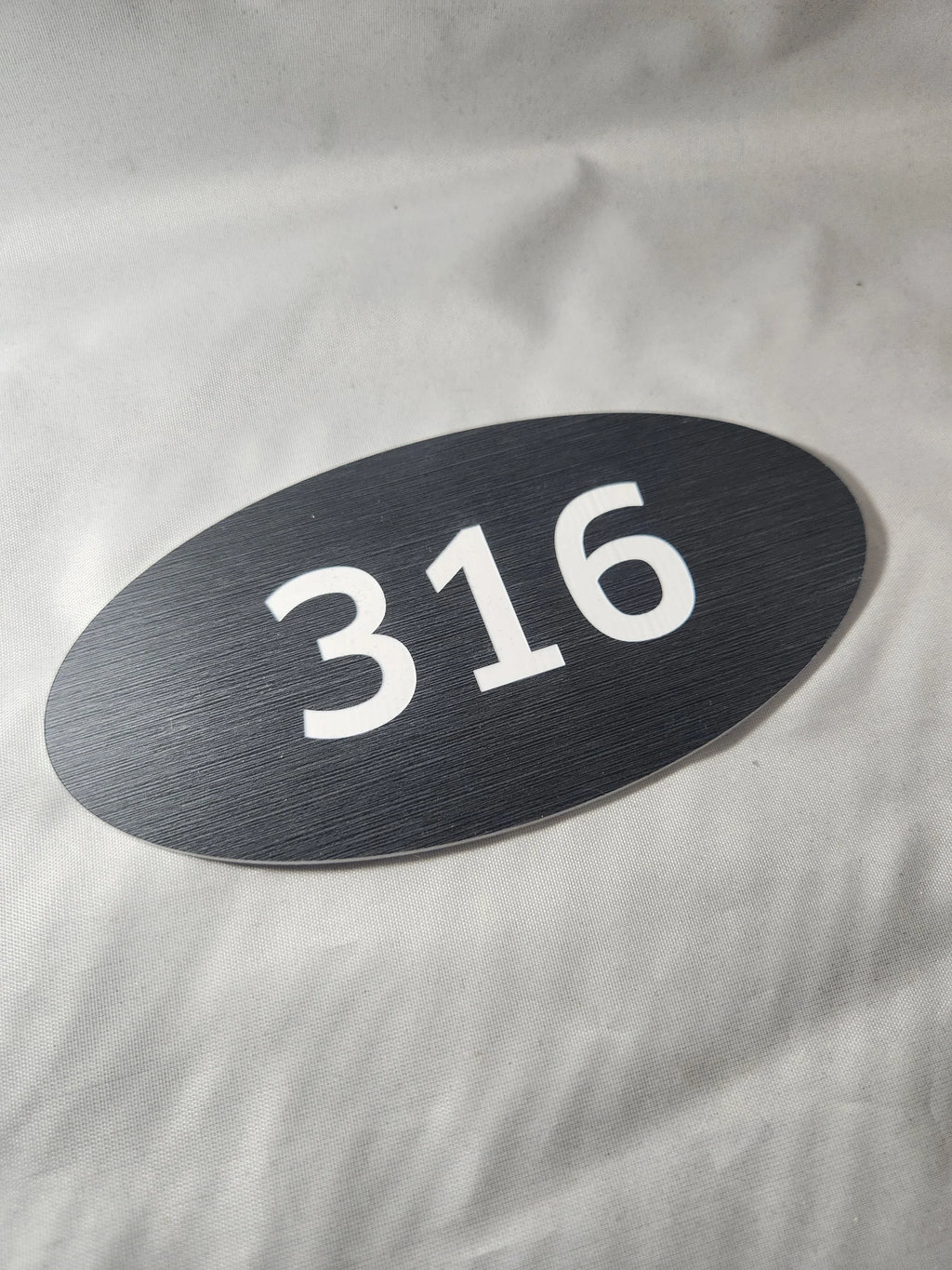 Oval black room number sign 316 with white text, ideal for office or hotel signage