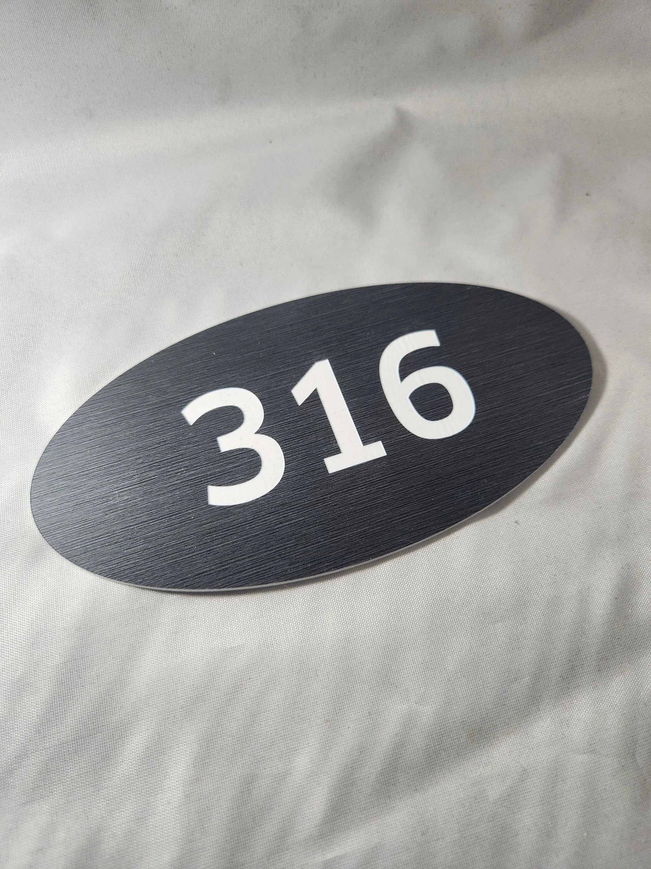 Oval black room number sign 316 with white text, ideal for office or hotel signage