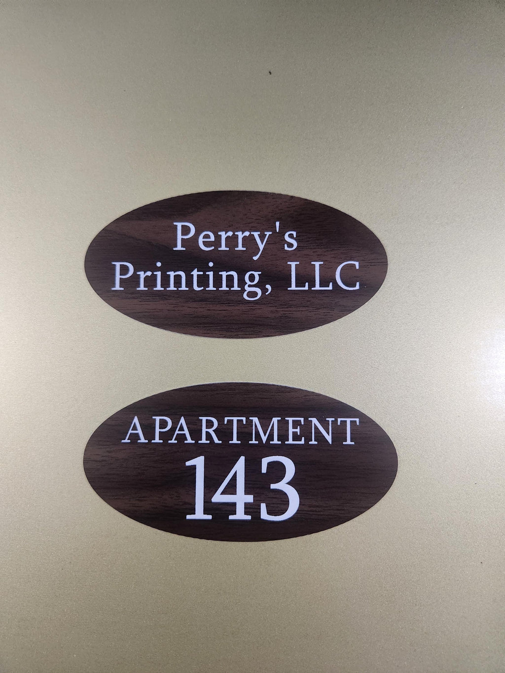 Oval wood grain apartment number and business door signs with white text on a gold background
