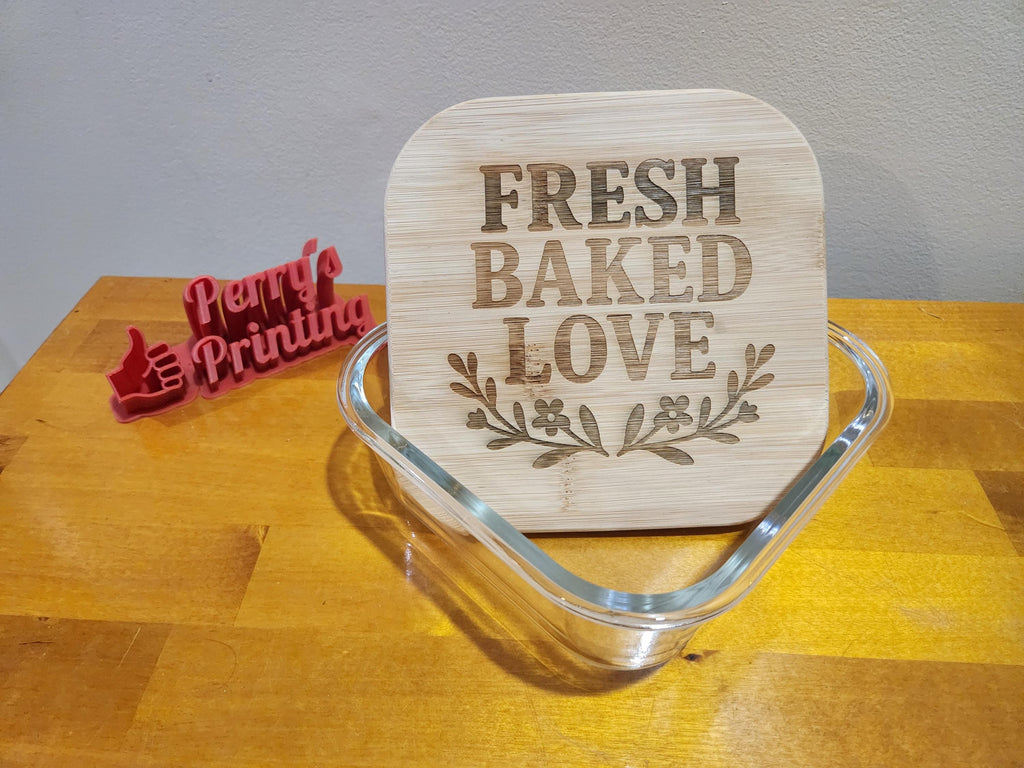 Laser engraved bamboo lid with 'Fresh Baked Love' design in glass dish, wooden table