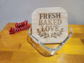 Laser engraved bamboo lid with 'Fresh Baked Love' design in glass dish, wooden table