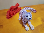3D printed snow leopard figurine and red Perry's Printing sign on wooden surface