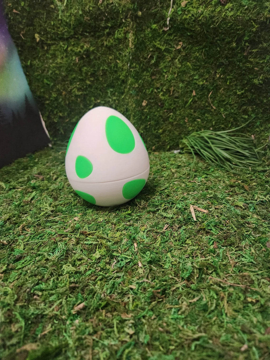 3D printed egg with green spots on artificial grass, custom decorative display