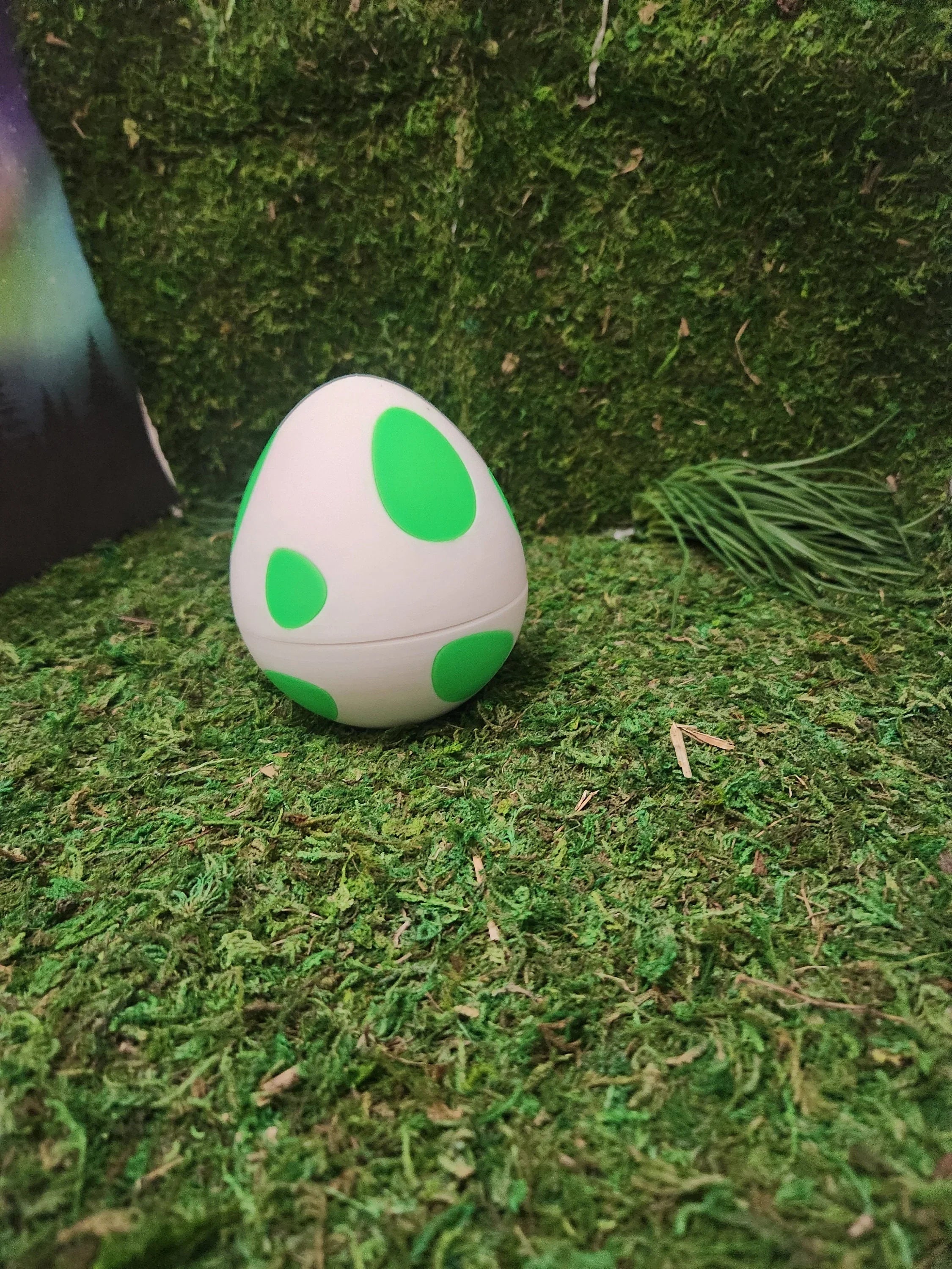 3D printed egg with green spots on artificial grass, custom decorative display