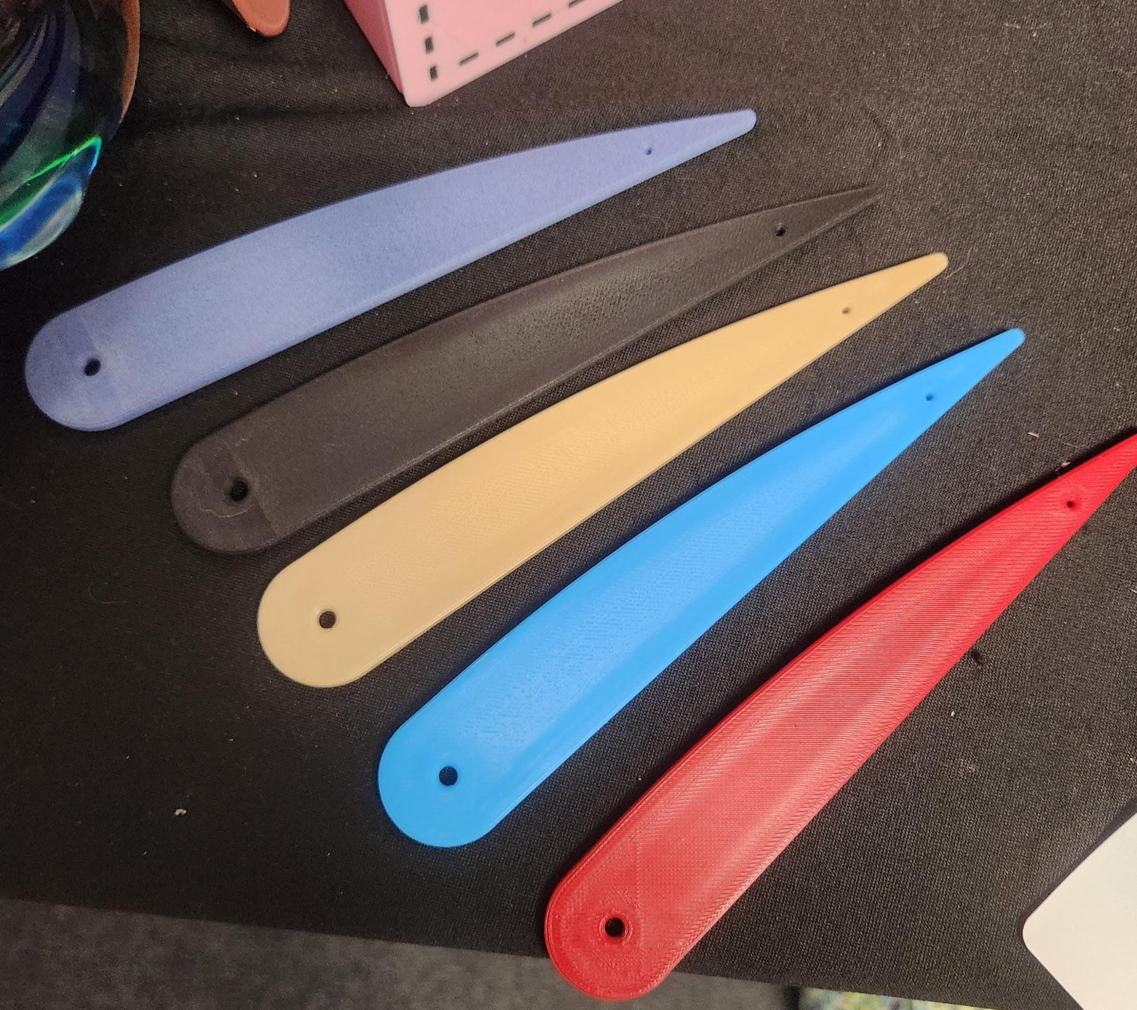 Set of five colorful 3D printed letter openers on black fabric background