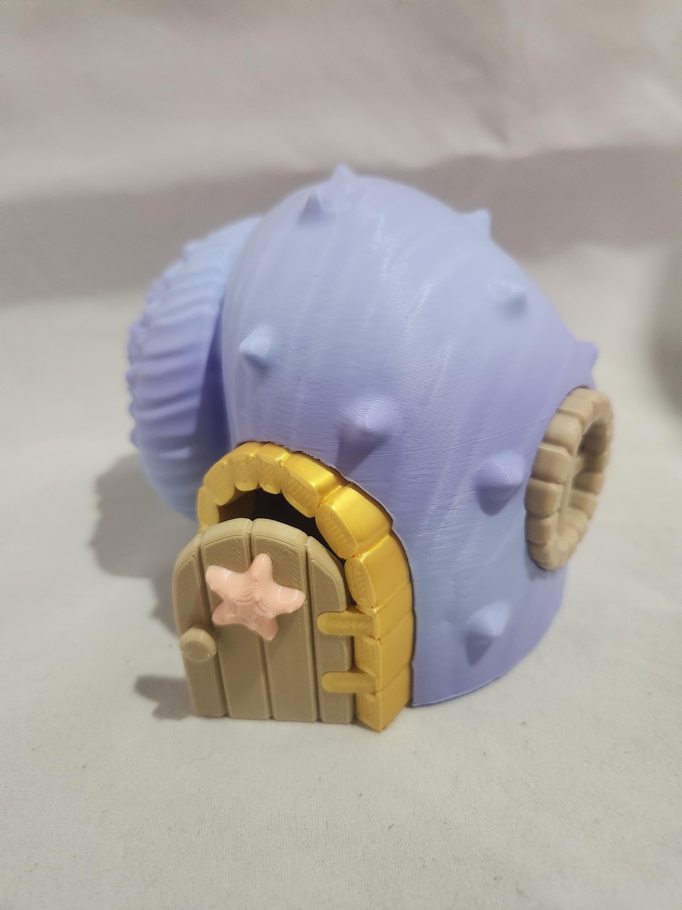 3D printed purple seashell house model with door and starfish detail on white background