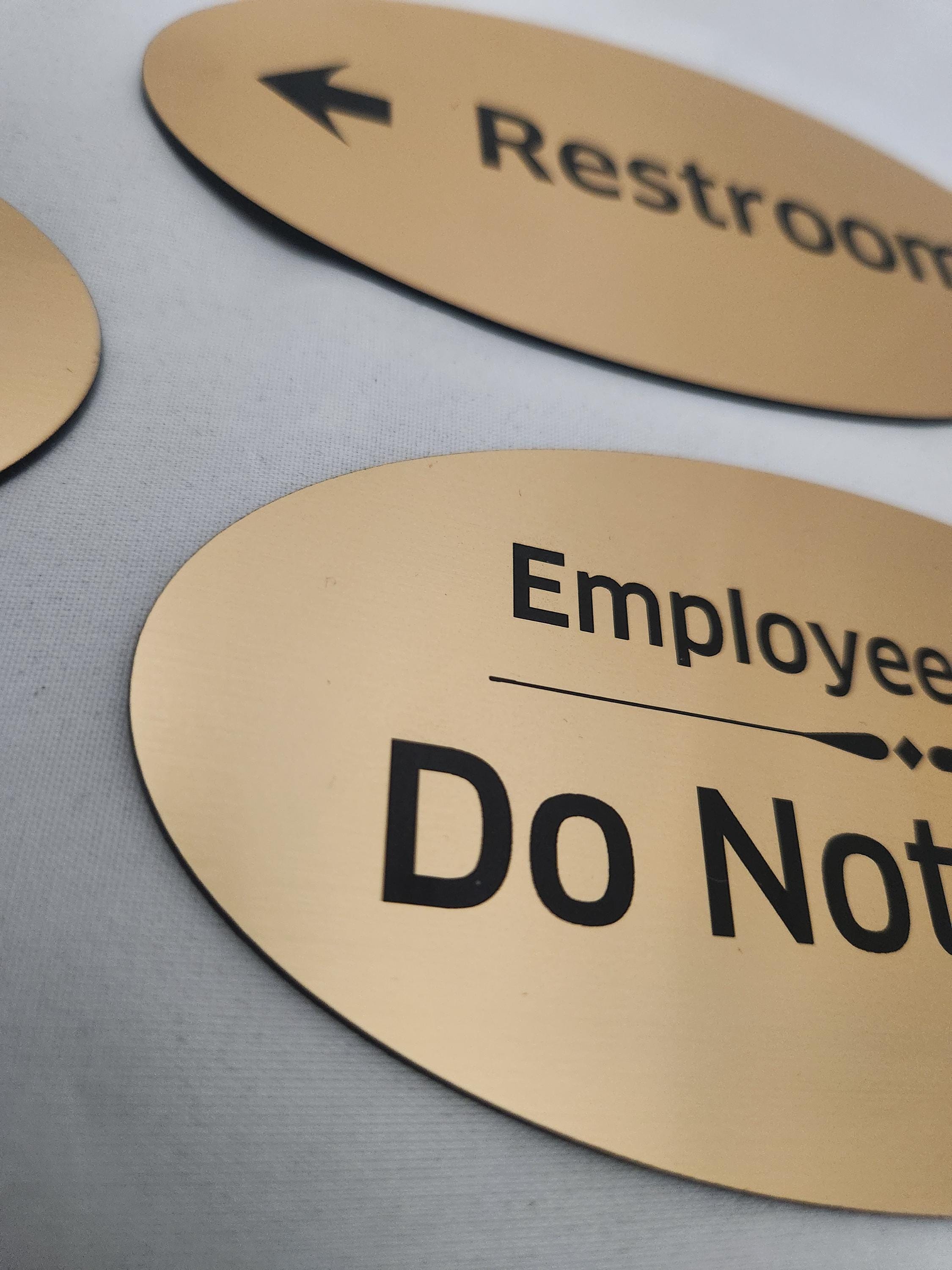 Custom laser engraved gold signs with black text for restrooms and employee areas