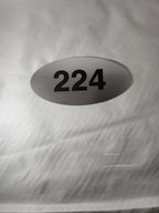 Oval brushed metal room number sign 224 with bold black numbers on a white background