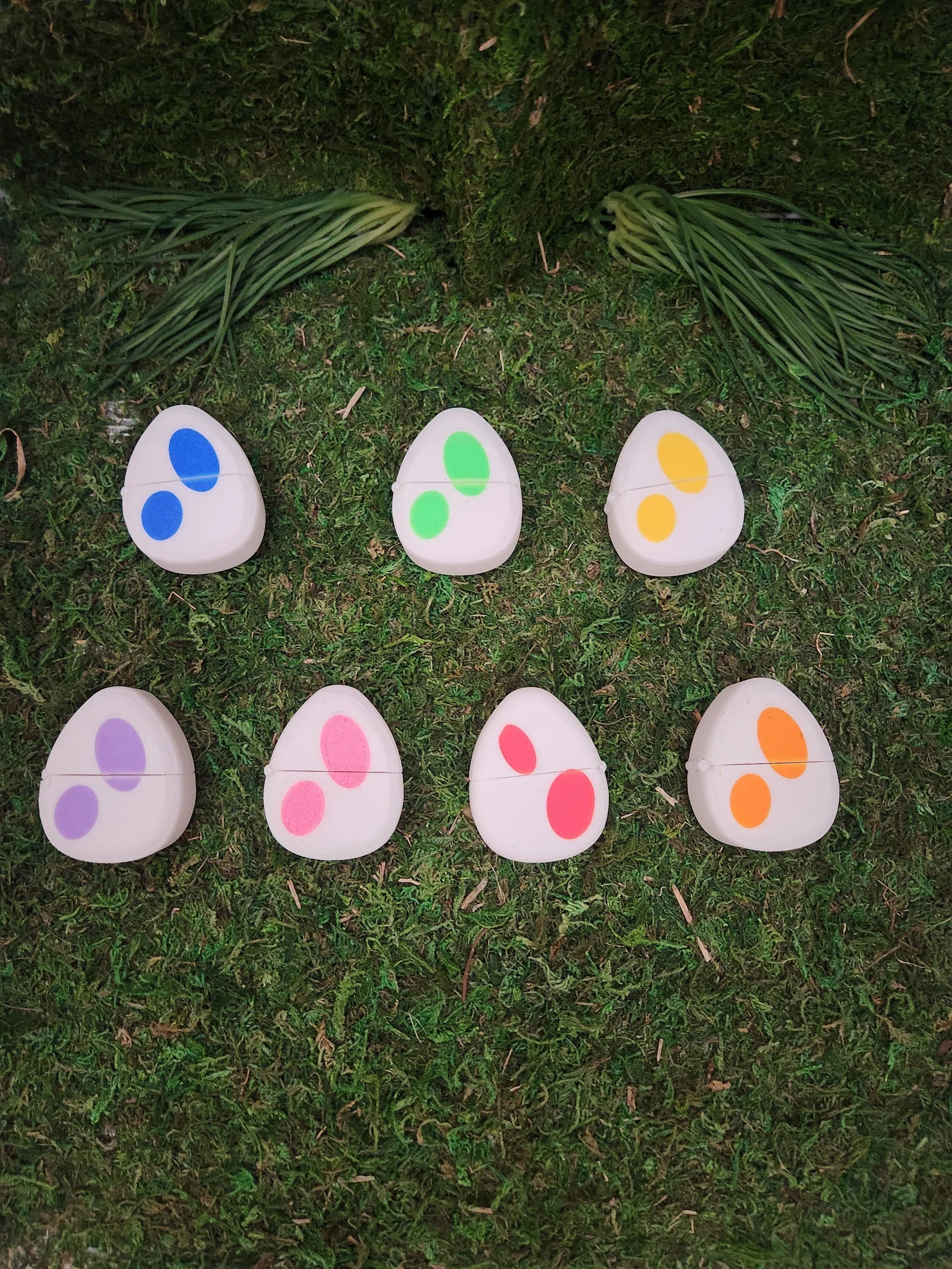Colorful spotted egg-shaped 3D printed tokens on grass, assorted pairs for matching game
