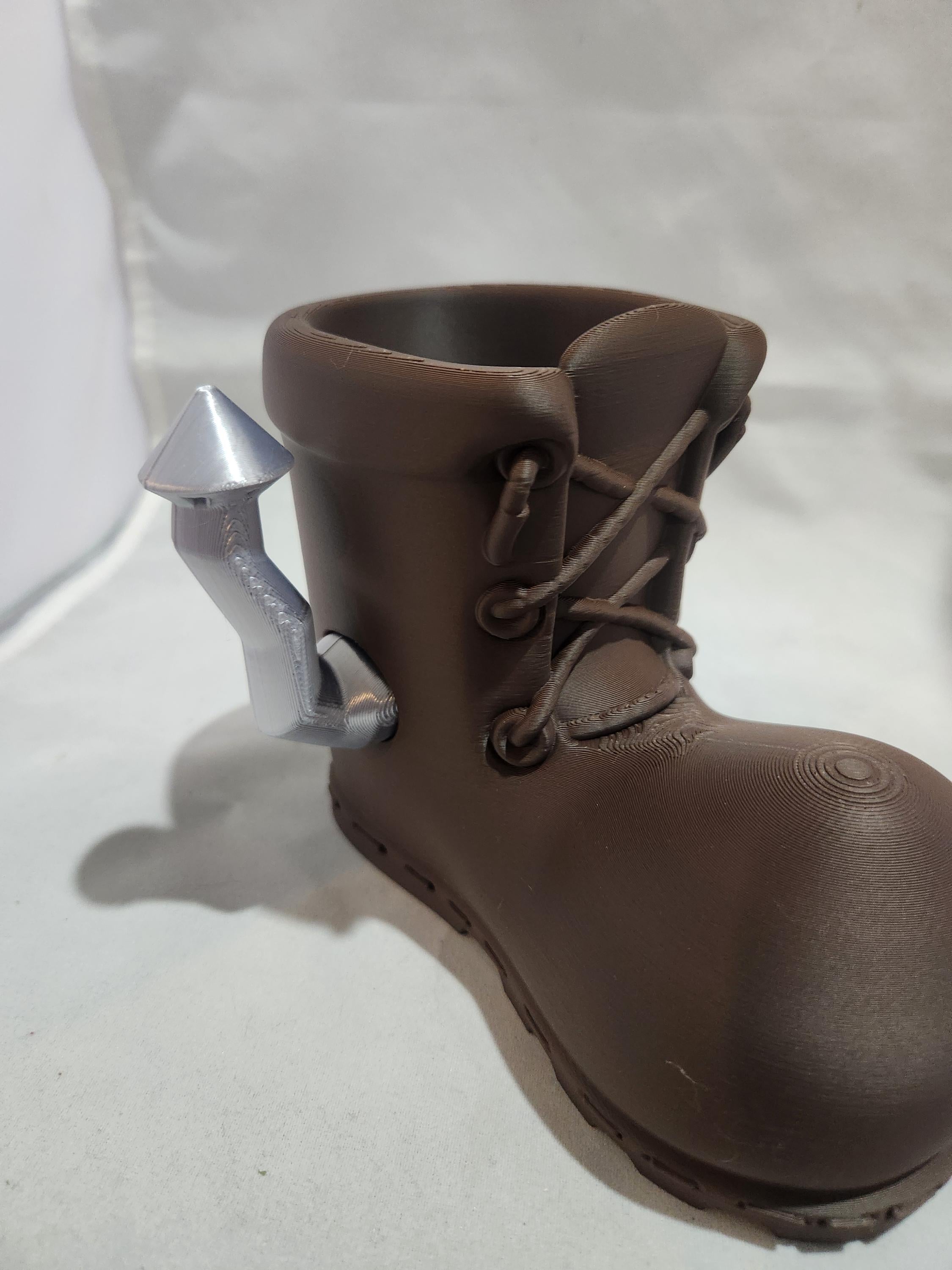 3D printed brown boot-shaped holder with a silver rocket detail