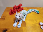 3D printed flexible leopard figurine with colorful spots on a wooden surface