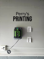 Wall-mounted battery charger and storage holders on gray wall, outlet with cord plugged in