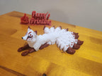 3D printed nine-tailed fox figurine with white body and brown accents on wood table