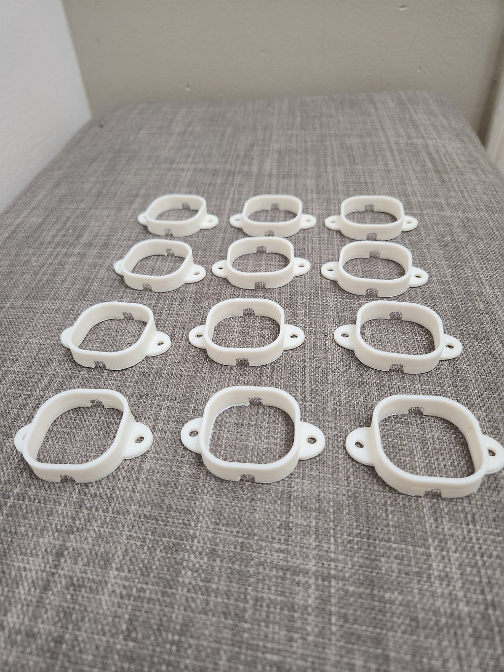 Set of white 3D printed plastic brackets arranged on a gray textured surface