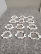 Set of white 3D printed plastic brackets arranged on a gray textured surface