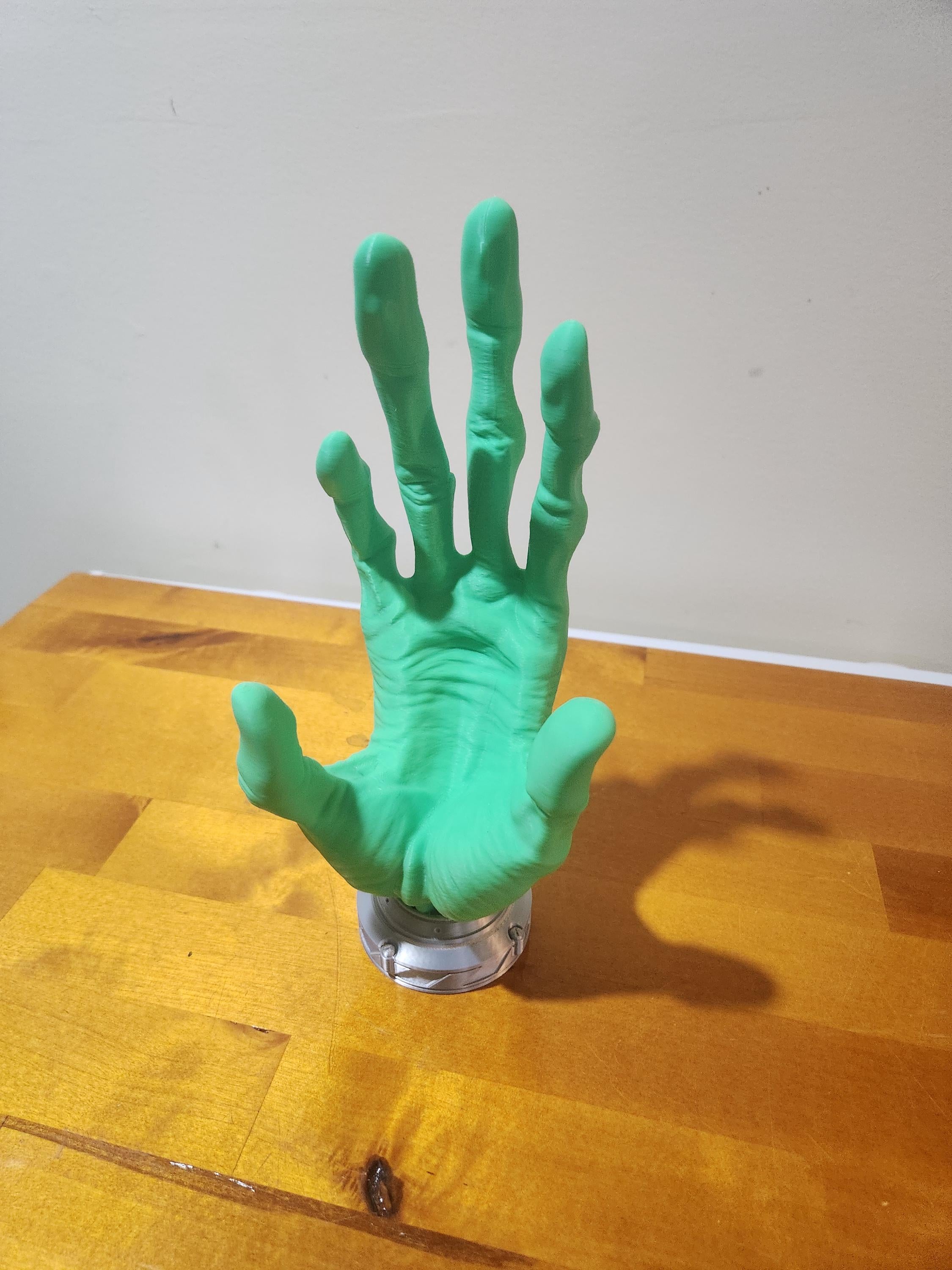 Green 3D printed hand sculpture on wooden surface, custom decor or display piece