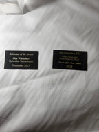 Custom engraved award nameplates on white cloth background, personalized for recognition.