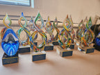 Colorful art glass awards with gold plaques for service to education, displayed on a table.