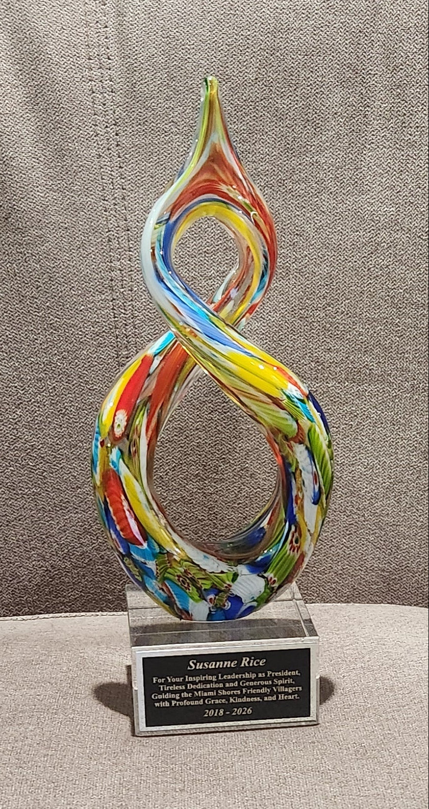 Handcrafted helix-shaped multicolor art glass award with a custom engraved silver plaque for Susanne Rice on a clear crystal base
