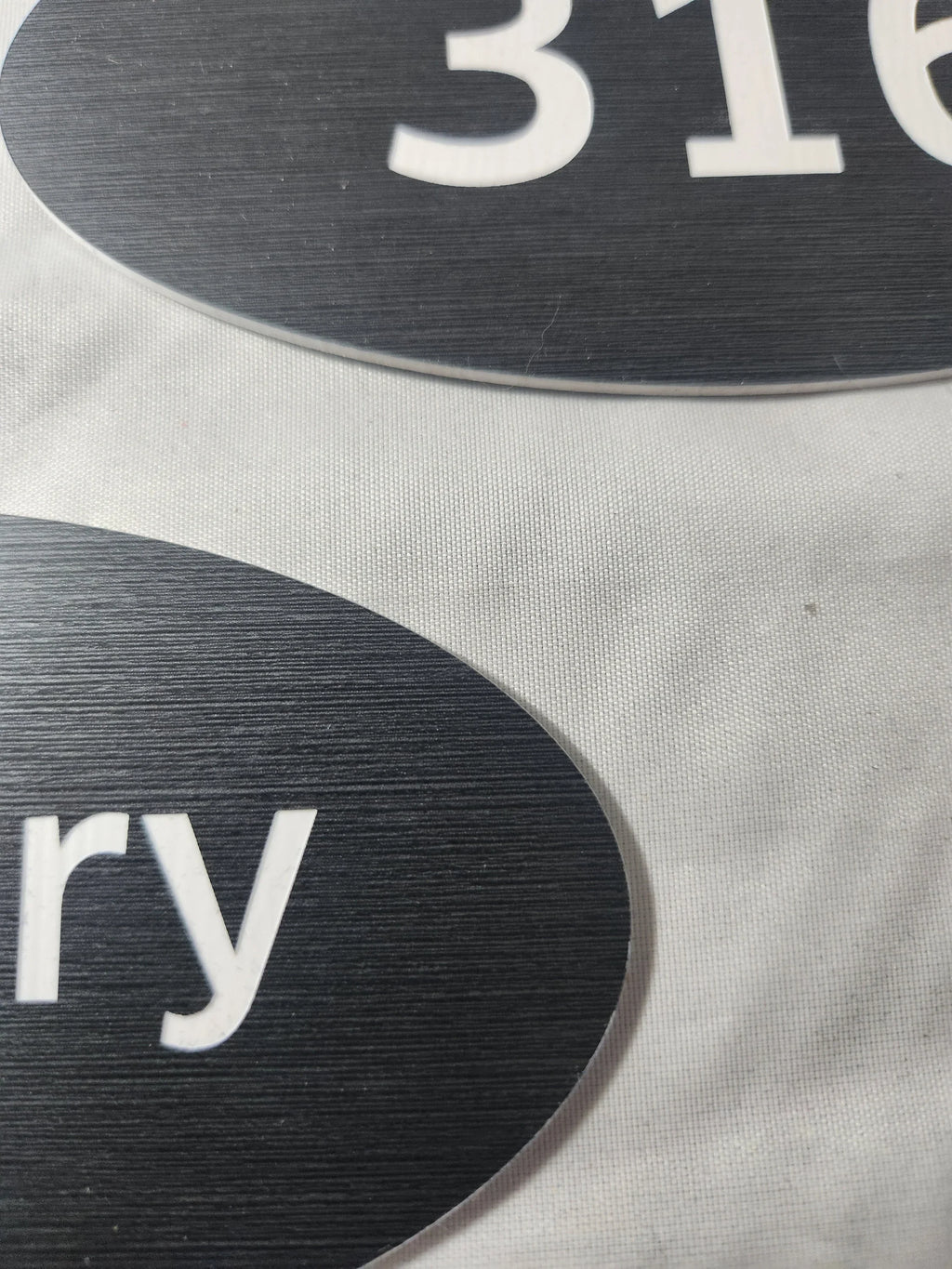 Close-up of custom black engraved signs with white text and brushed texture