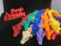 Colorful 3D printed articulated dragon figures on black fabric beside a red Perry's Printing sign