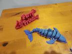 3D printed blue articulated whale and red sign on wooden table
