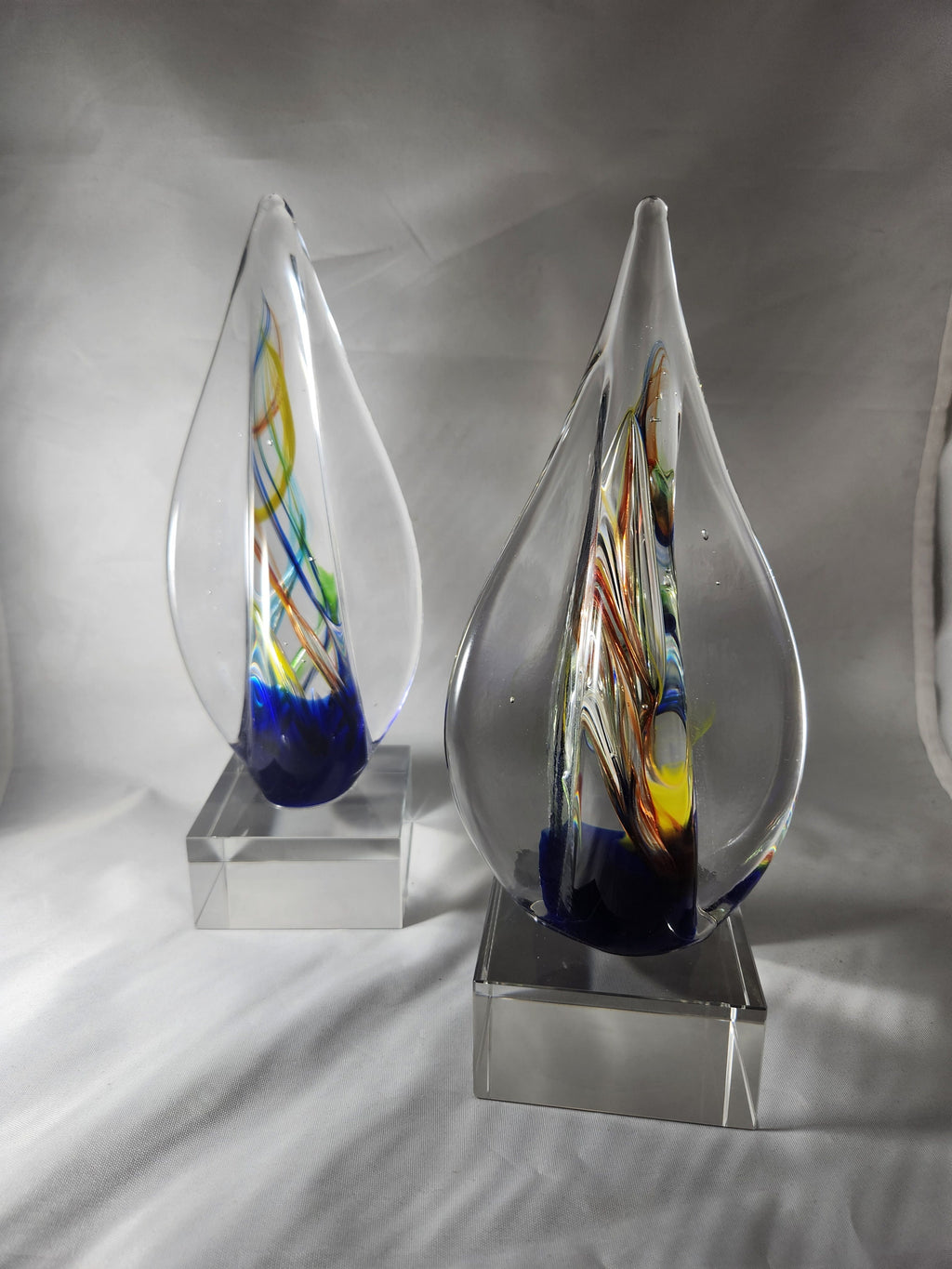 Colorful glass art awards with abstract swirls on clear bases, ideal for custom engraving