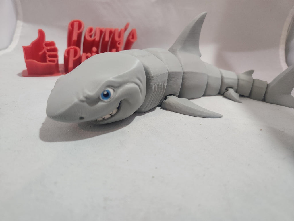 3D printed articulated shark figurine with cartoon smile and blue eyes on white background