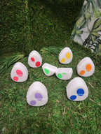 Colorful polka dot plastic egg containers on artificial grass with leafy backdrop