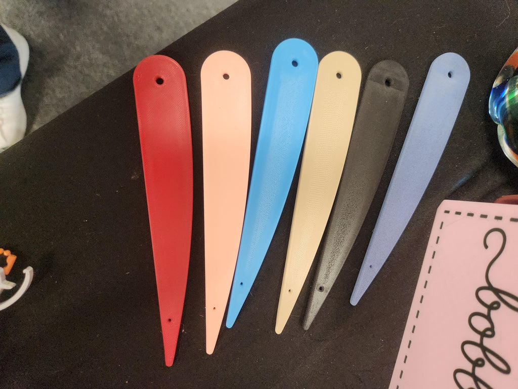 Assorted 3D-printed plastic shoehorns in red, peach, blue, beige, black, and gray on display