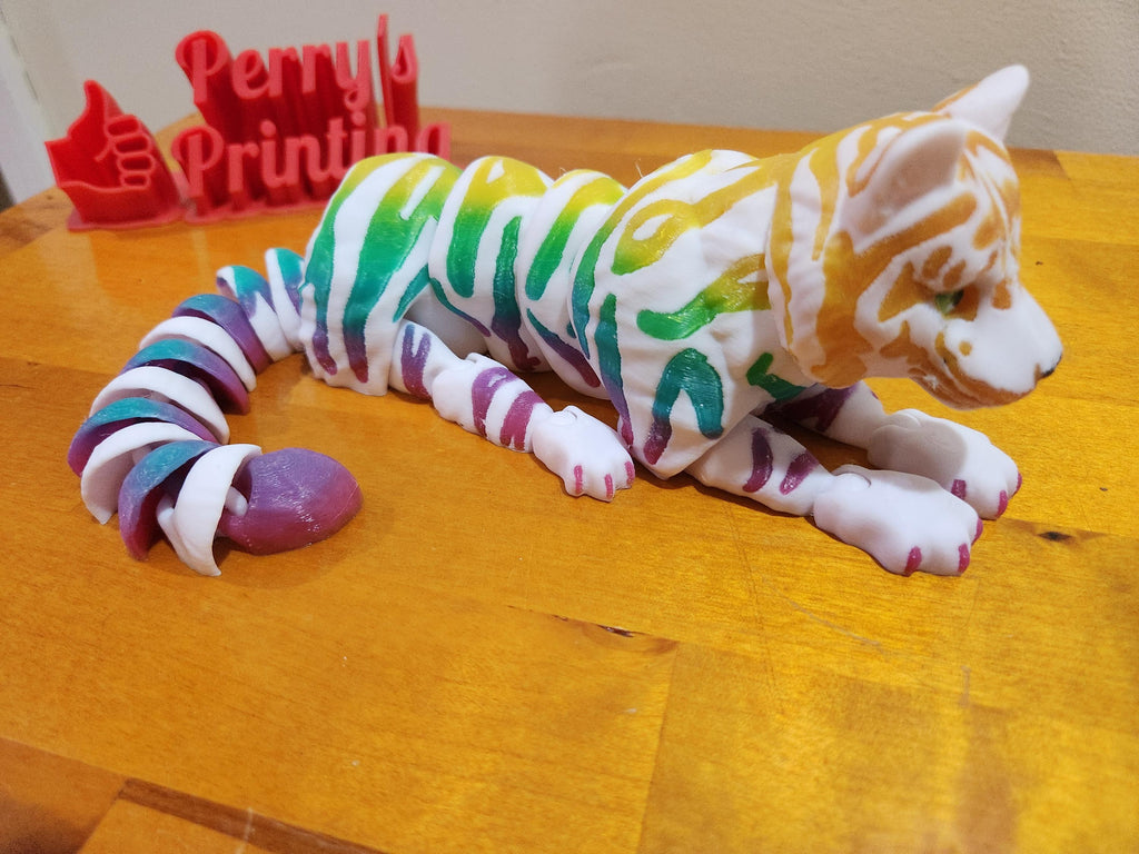 Colorful 3D printed articulated tiger figurine with rainbow stripes on a wooden surface