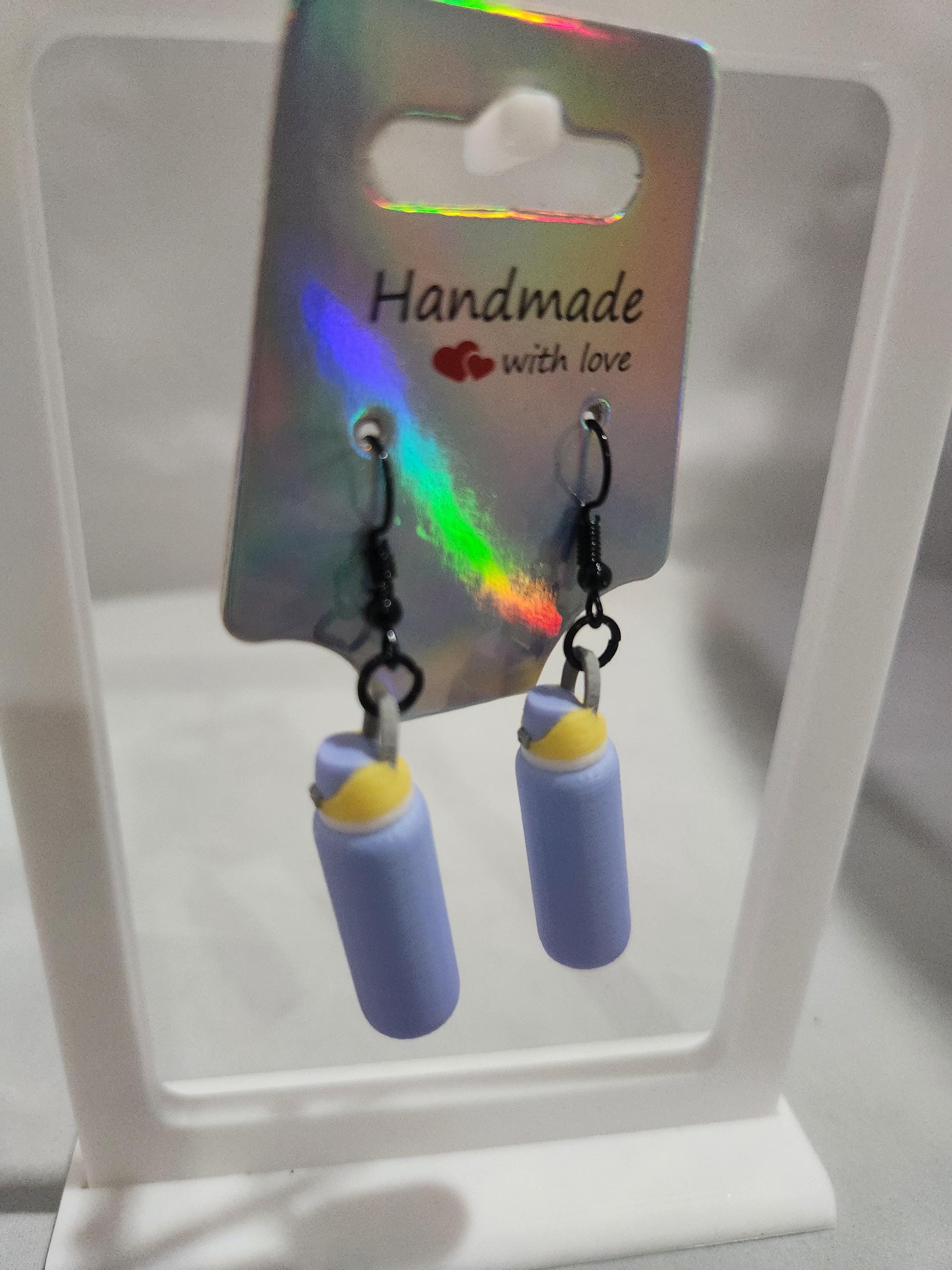 Handmade earrings with purple and yellow 3D-printed bottle charms on display card