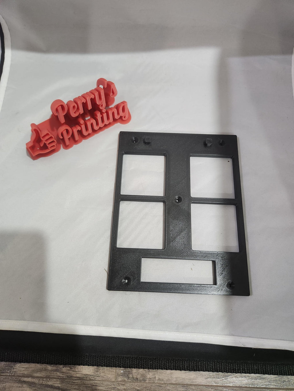 3D printed red sign with text and black plastic wall plate on a white background