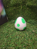 3D printed white egg with green spots on artificial grass background