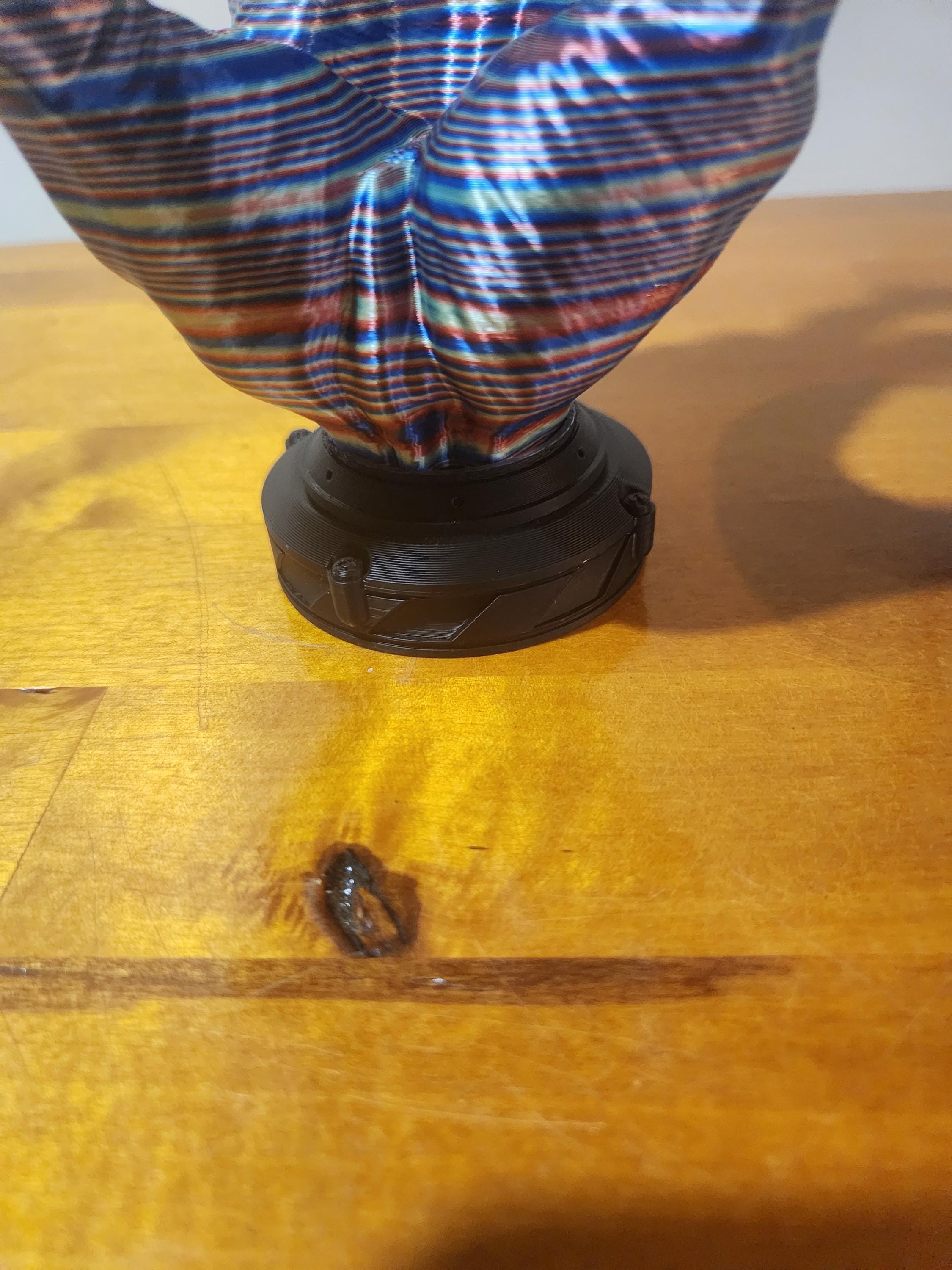 3D printed colorful abstract sculpture on wooden surface with black circular base