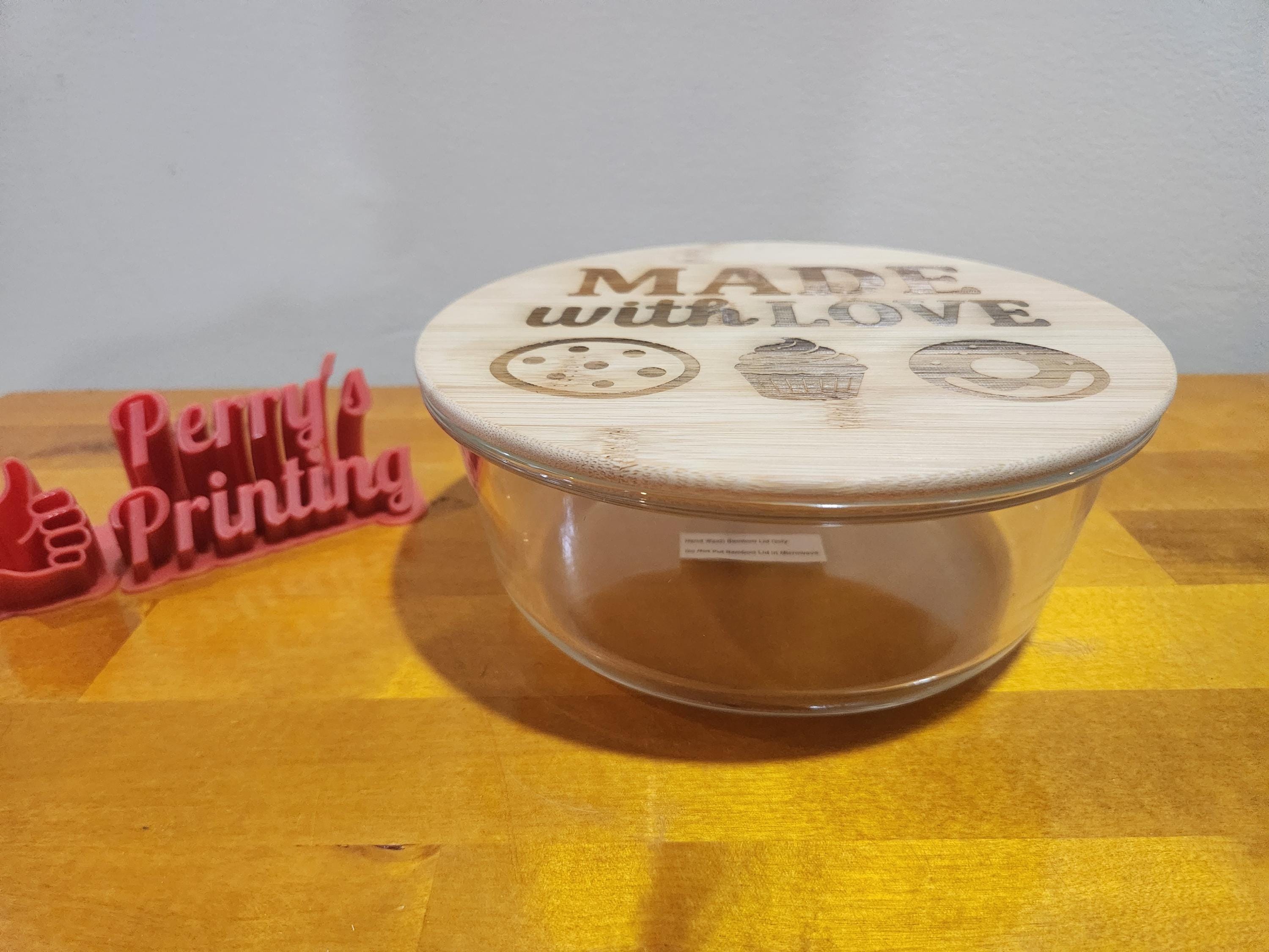 Glass container with engraved bamboo lid, cookie and cupcake design, on wooden table