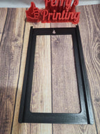 3D printed black rectangular frame with wall mount slot on wood surface