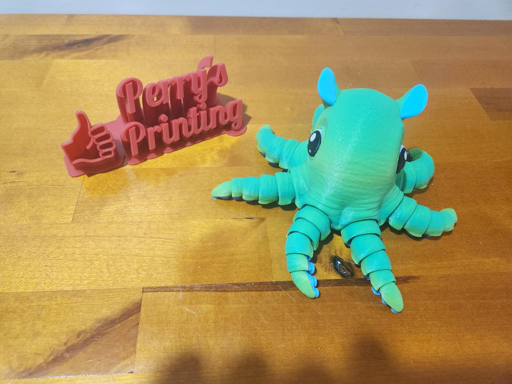 3D printed green articulated octopus and red sign on wooden table