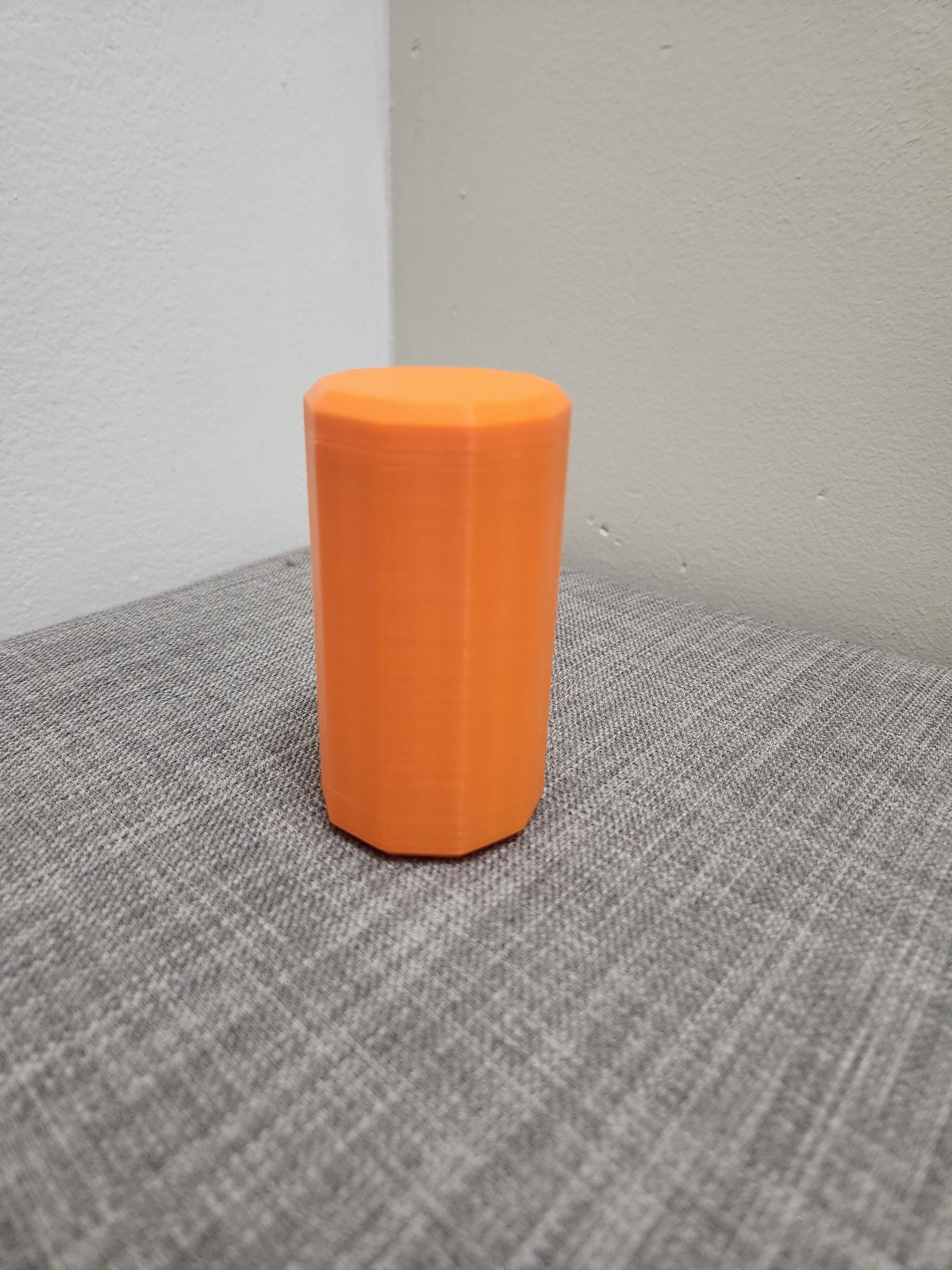Orange 3D printed octagonal container on a gray fabric surface
