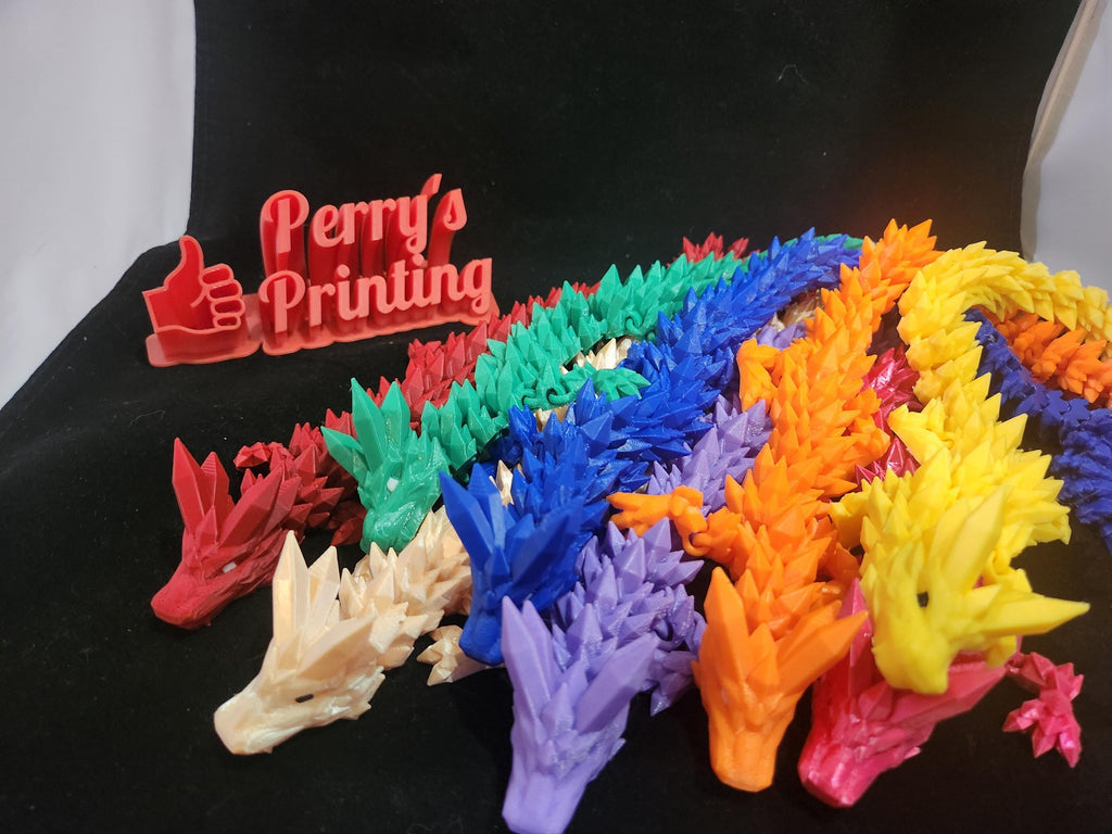 Colorful 3D printed dragon models and Perry's Printing sign on black background.