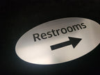 Brushed metal restroom sign with arrow, laser engraved, directional signage