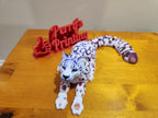 3D printed articulated snow leopard figurine with a red 3D printed sign on wood table