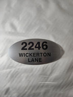 Oval brushed metal address sign with 2246 Wickerton Lane in black engraved text