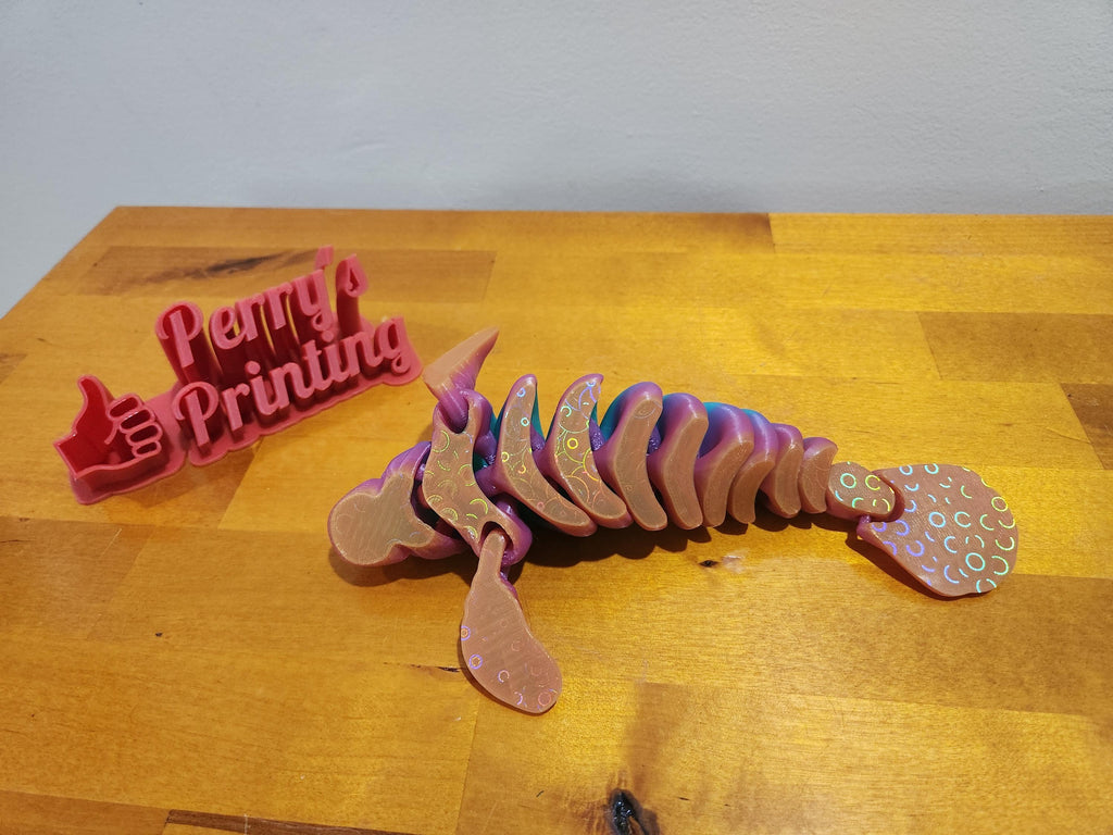3D printed articulated axolotl figure with iridescent finish on wooden table