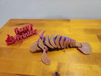 3D printed articulated axolotl figure with iridescent finish on wooden table