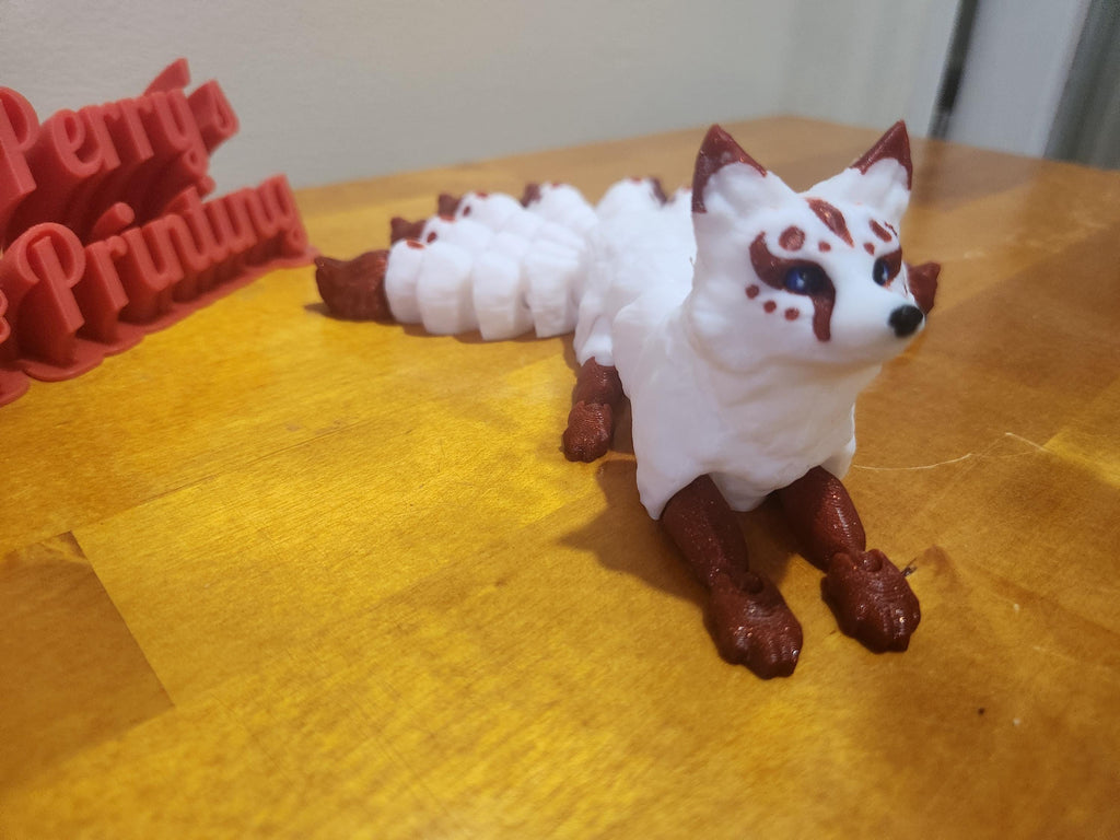 3D printed white and red fox figurine with painted face markings on a wooden surface