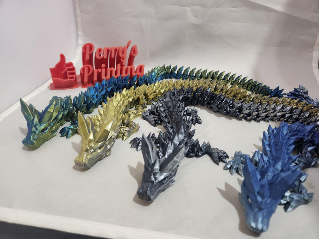 Colorful 3D printed articulated dragon figures in front of Perry's Printing sign