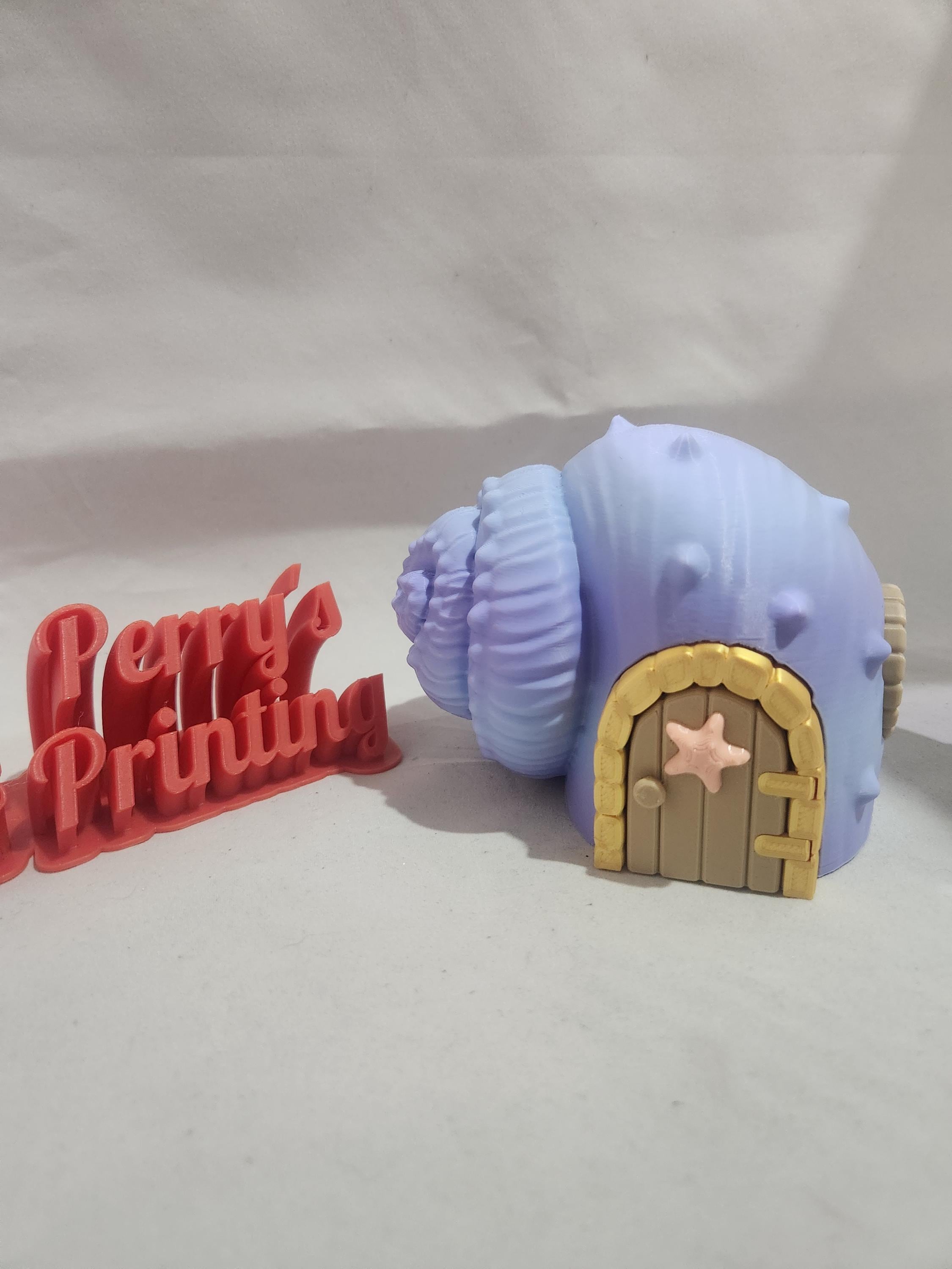 3D printed pastel purple seashell house with starfish door beside red 3D printed sign