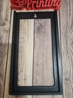 3D printed black rectangular frame with mounting hole on wood surface